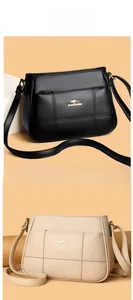 Detail of stitched crossbody bag with gold kangaroo logo in black and beige