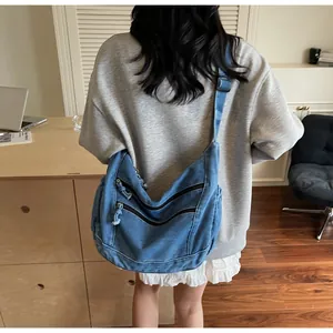 Detail of blue denim crescent crossbody bag with decorative parallel metal zippers