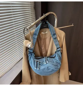 Blue denim crescent crossbody bag with multiple zip pockets and adjustable strap
