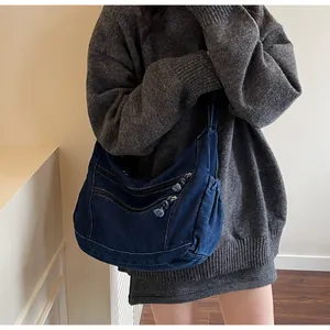 Detail of dark blue denim hobo bag featuring twin front zippers and casual hobo silhouette
