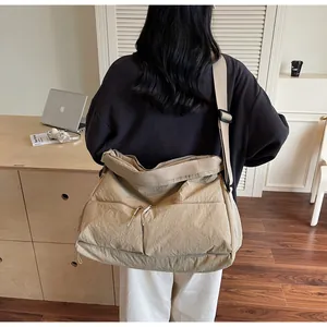 Detail view of khaki crossbody bag with dual front zipper pockets and wide nylon strap