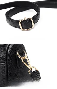 Detail of black pebbled leather texture with golden adjustable strap and detachable hook