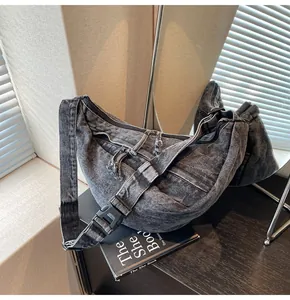 Detailed view of washed black denim crossbody bag with textured fabric and metal zipper