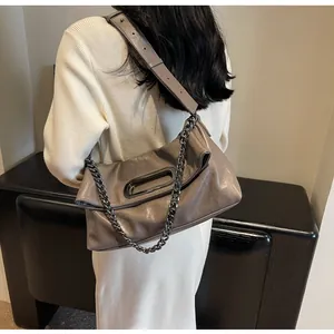 Detail der taupefarbenen Ledertasche mit ovalem Metallgriff und Kettenriemen