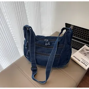 Detailed view of dark blue denim tote bag with triple zippers and adjustable shoulder strap