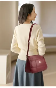 Detail of burgundy crossbody bag with lychee leather texture and golden kangaroo logo