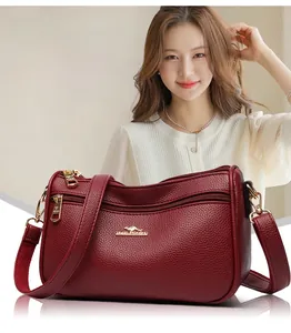 Detail of burgundy pebbled leather bag with gold hardware and multiple zip pockets