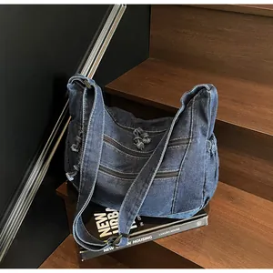 Detail of dark blue denim tote bag with triple zipper pockets on wooden stairs