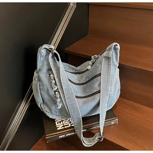 Detail of light blue denim hobo bag with triple zipper pockets on wooden stairs