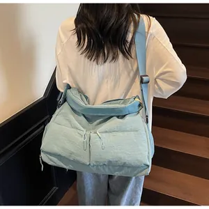 Detail of light blue nylon crossbody bag with dual front zipper pockets on model