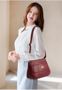 Detail of burgundy leather crossbody bag featuring quilted stitching and golden logo