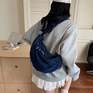 Minimalist dark blue denim half-moon crossbody bag with adjustable strap and tassel zip