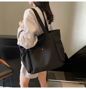 Detail showing the large capacity black nylon tote bag with drawstring side pocket details