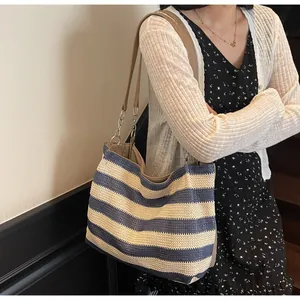 Close-up of blue and beige striped woven beach bag with metal chain shoulder strap