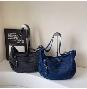 Detail view of washed denim tote with three zipper pockets and adjustable strap