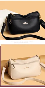 Detail of multi-zippered crossbody bag showing litchi grain texture and gold hardware