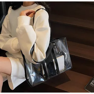 Gros plan d'un cabas en PVC transparent avec bordure noire et pochette sur des marches en bois