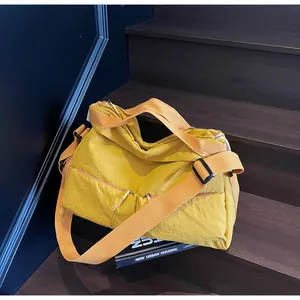 Close-up of mustard yellow nylon tote bag with multiple zip pockets and wide strap