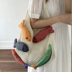 Beige hohlgestrickte Tragetasche mit fünf bunten Fisch-Anhängern für den Sommerstrand