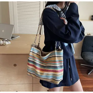 Close-up of a colorful striped woven straw tote bag with chain leather shoulder straps