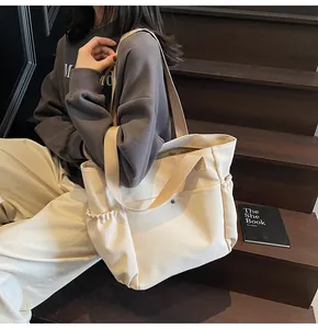 Detail view of beige canvas tote bag showing snap front pocket and side drawstring pocket