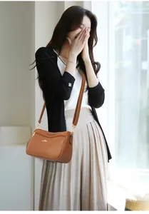 Detail of caramel lychee grain leather crossbody bag with elegant gold logo and hardware