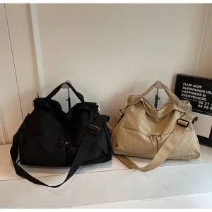 Detail of large nylon tote bags in black and khaki with multiple zipper pockets