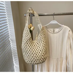 Close-up of beige hollow knit paper rope tote bag featuring a decorative knot on the strap