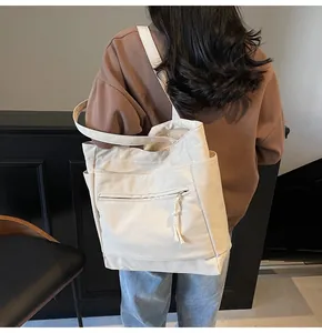 Détail du sac cabas en toile crème avec poche zippée et élégantes franges décoratives