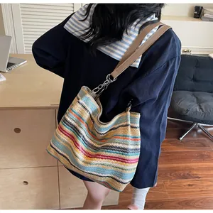 Detail of colorful striped woven beach bag with yellow leather strap and metal rings