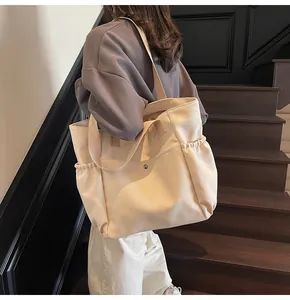 Close-up of a cream nylon tote bag with multiple pockets and functional shoulder straps