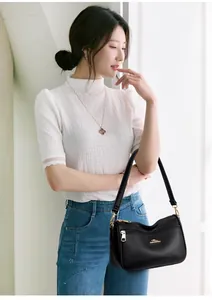 Close-up of black lychee leather handbag texture with golden kangaroo logo and hardware