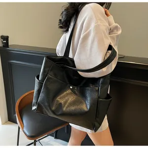 Close-up of black leather tote bag with functional side pockets for daily commute