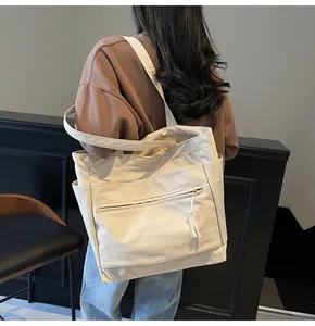 Vue détaillée du grand sac cabas en toile avec poche éclair et longs pompons