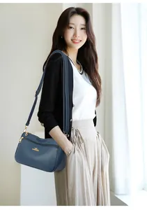 Detail shot of navy blue lychee grain leather crossbody bag with golden kangaroo logo