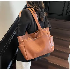 Detail view of large brown tote bag with front pocket and natural leather texture