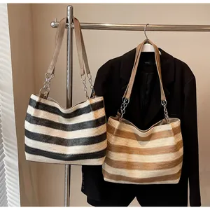 Detail of woven tote bags with leather straps and metal chains in stripe patterns