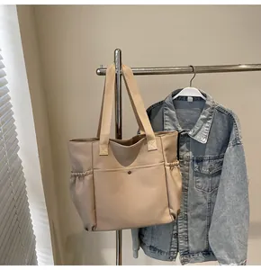 Detail of beige nylon tote bag with metal snap button pocket and wide woven handles