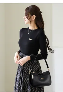Detail of black pebbled leather handbag with gold logo and knit sleeve texture