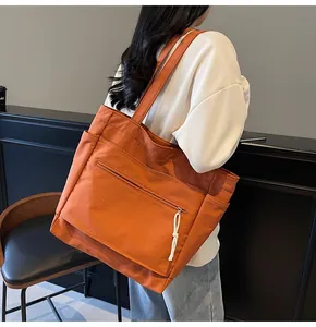 Gros plan d'un sac cabas en toile orange avec poches latérales et poche frontale zippée