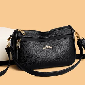 Detailed view of black pebbled leather crossbody bag with gold kangaroo metal logo