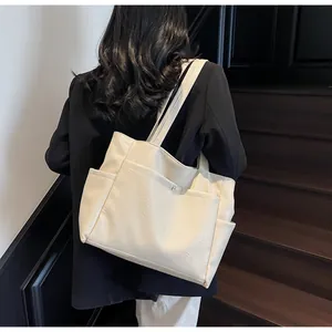 Detail view of cream tote bag with wrinkled texture and magnetic buckle pocket