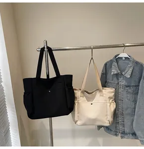 Detail view of black and cream nylon tote bags with functional front metal snap pockets