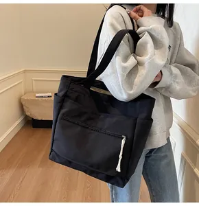Détail du sac cabas en toile noire avec poches latérales et tirette en corde blanche