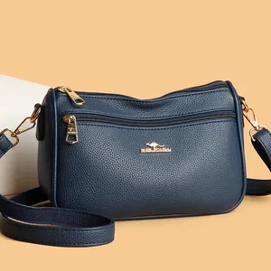 Detail shot of navy blue crossbody bag featuring lychee grain texture and golden logo