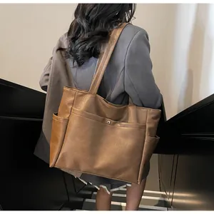 Detail of a brown vintage tote bag with side pockets and smooth textured leather finish
