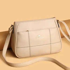 Detail of beige crossbody bag with litchi grain texture and golden kangaroo logo
