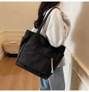 Détail d'un grand cabas en toile noire avec pompon blanc et poche zippée pratique