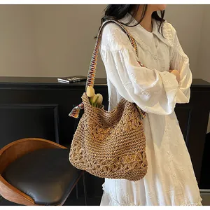 Detail of woven straw hobo bag with hollow knit patterns and colorful braided strap