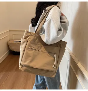Détail d'un grand cabas en toile kaki avec poche avant zippée et compartiments latéraux